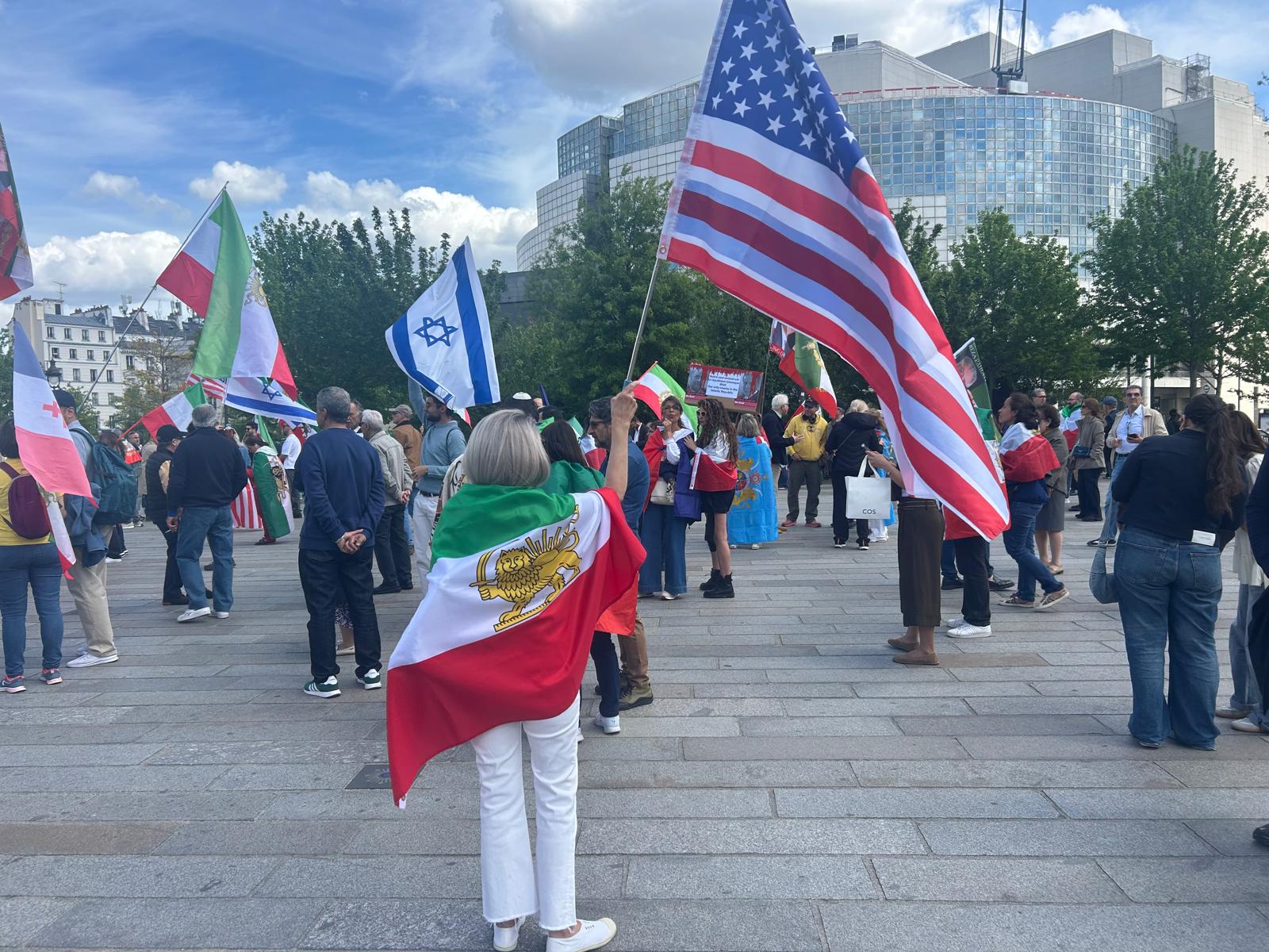 A woman wrapped in a shah-era flag at the rally in Place de la Bastille, Paris, April 19, 2026. Photo by Amelie Botbol.