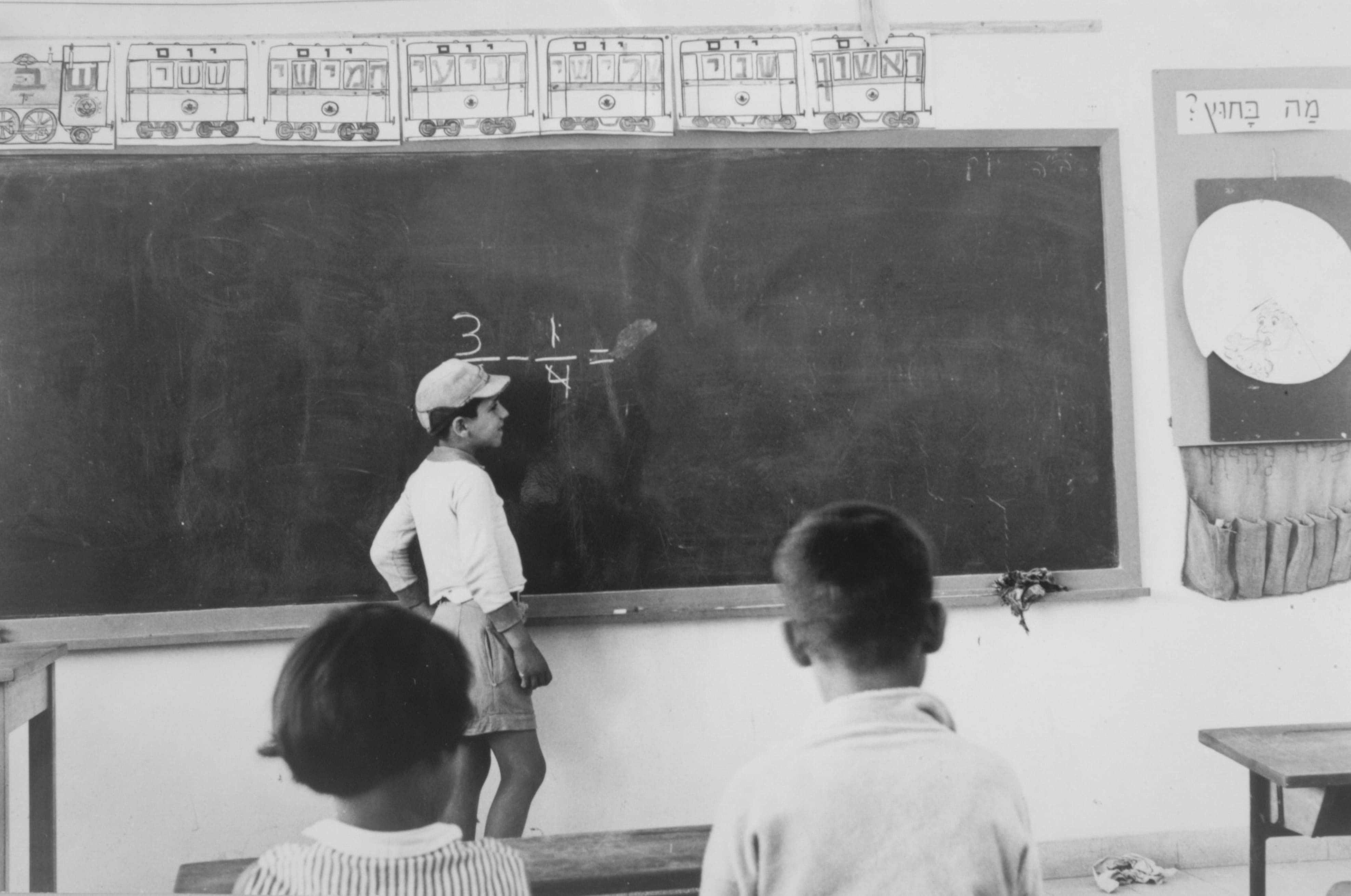 A student solves an arithmetic problem on a chalkboard, Tzur Hadassah, 1961. Credit: David Hirschfeld, KKL-JNF Photo Archive.