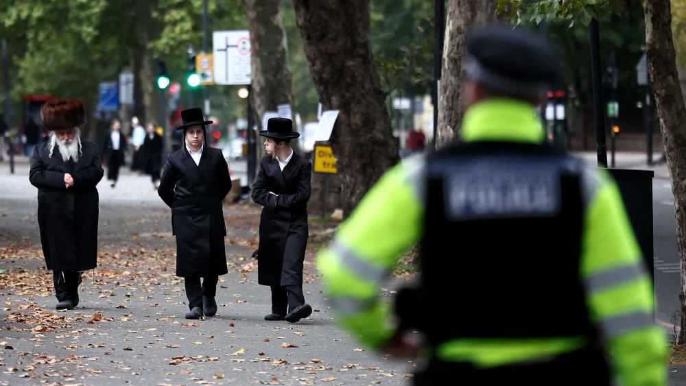 Members of the local Jewish community look on as Metropolitan Police officers patrol the streets in Stamford Hill, north London on October 2, 2025. Photo by HENRY NICHOLLS/AFP via Getty Images.