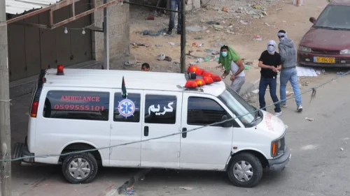 Palestinians throw rocks from behind an ambulance during a riot in Qalandiya. Credit: IDF.