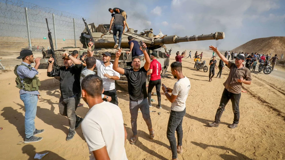 Palestinians take control of an IDF tank after breaching the Israeli border fence from Khan Yunis in the southern Gaza Strip, Oct. 7, 2023. Photo by Abed Rahim Khatib/Flash90.