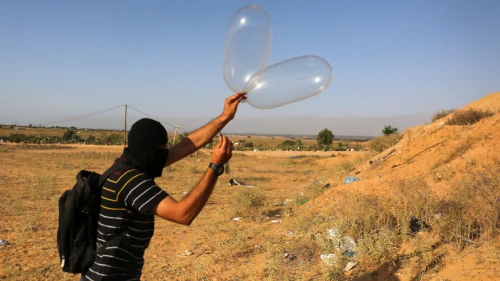 Palestinians in Gaza attach a balloon to flammable materials to be flown towards Israel. These incendiary devices have caused destruction to trees, animals, the land and the environment. June 17, 2018. Photo by Abed Rahim Khatib/Flash90.