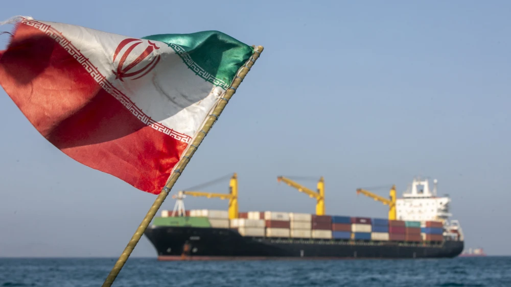 An Iranian flag flutters in the wind as ships remain anchored in the Strait of Hormuz near Larak Island, Iran, on May 16, 2026. Credit: Majid Saeedi/Getty Images.