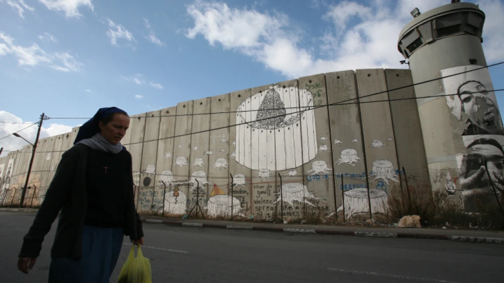 A nun hurries by the Judea and Samaria security barrier toward an IDF checkpoint on her way from Jerusalem to the Church of Nativity in Bethlehem, Dec. 11, 2008. Photo by Yossi Zamir/Flash90.