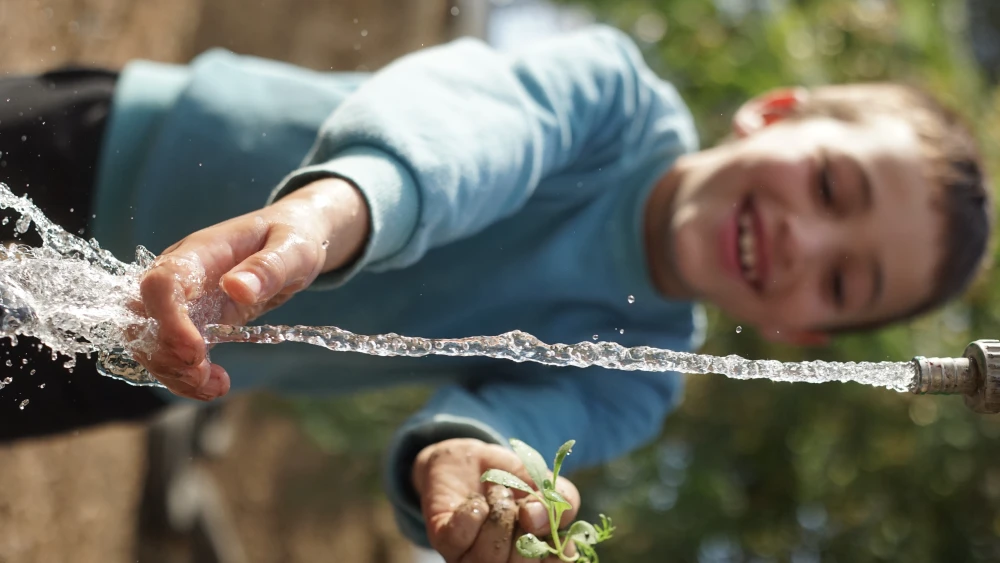A child plays with water, a precious resource in Israel. Credit: Jewish National Fund.
