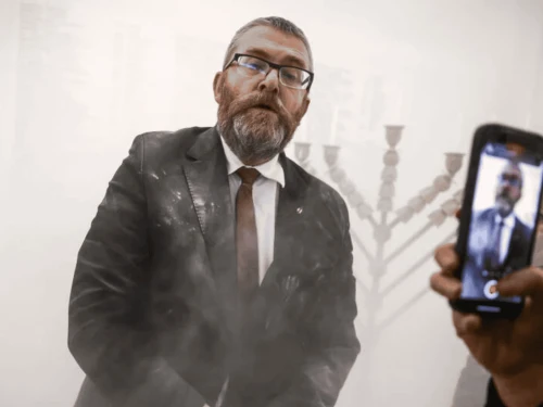 Grzegorz Braun stands next to a Hanukkah menorah after using a fire extinguisher on it inside the Polish parliament in Warsaw, Poland on Dec. 12, 2025. Photo courtecy of Rabbi Sholem Stambler.