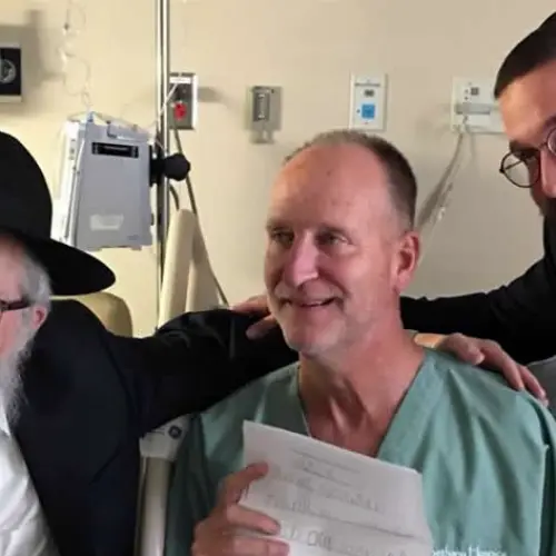Officer Dan Mead, center, holds a letter of thanks from second-grade students at Yeshiva Schools of Pittsburgh. He is flanked by Rabbi Yisroel Rosenfeld, left, and Rabbi Henoch Rosenfeld. Credit: Chabad.org/News.