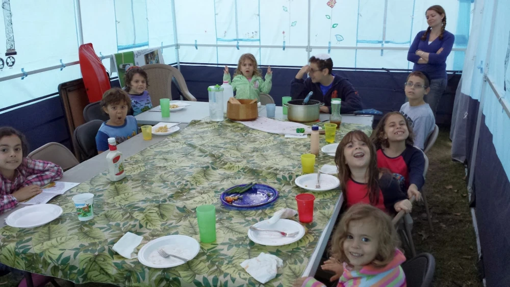 Children enjoying a sukkah. Credit: Sukkahsoftheworld.