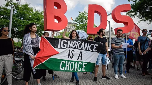 Protesters in Berlin hold a Palestinian flag and the initials of the anti-Israel BDS movement while then-Israeli Prime Minister Benjamin Netanyahu was visiting Germany in August 2019. Credit: Israel Hayom.