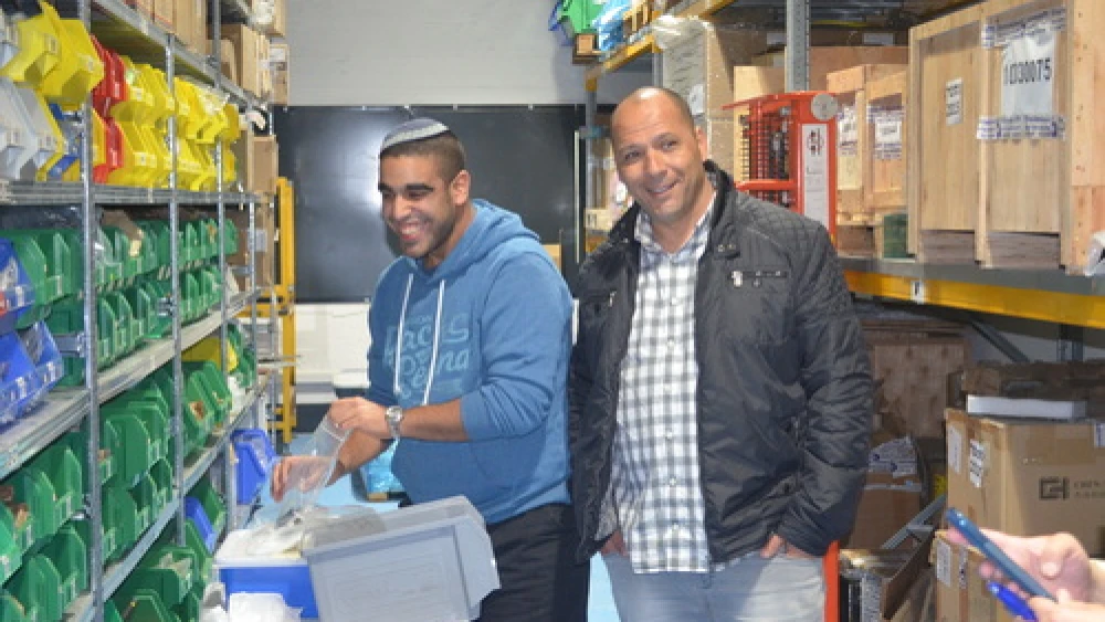 Chen Orpaz (left) with IDF Lt. Col. (Ret.) Ariel Almog, founder of "Special in Uniform," in the warehouse of the Rehovot-based technology company IDEA. Orpaz, who has an intellectual disability, now works at IDEA after picking up the skills he needed from working in the warehouse on an air force base as part of the Special in Uniform project. Credit: Courtesy Jewish National Fund.