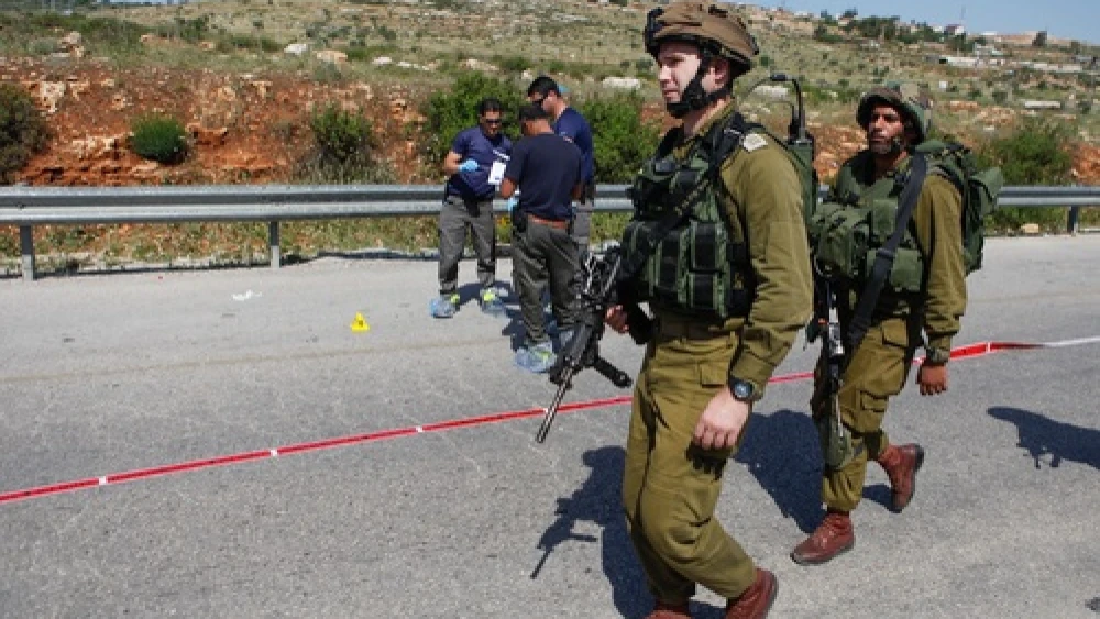 Israeli security forces inspect the site of a terror attack, at a bus stop at the Tapuach Junction on April 30, 2013. The Palestinian terrorist stabbed a 31-year-old Israeli man to death at a bus stop, police said. Credit: Flash90.