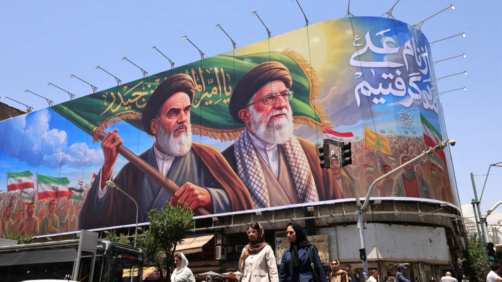 Iranians in central Tehran cross the street past a large billboard showing portraits of the Islamic Republic's late supreme leaders, Ayatollah Ruhollah Khomeini and Ayatollah Ali Khamenei, June 8, 2026. Photo by Atta Kenare/AFP via Getty Images.