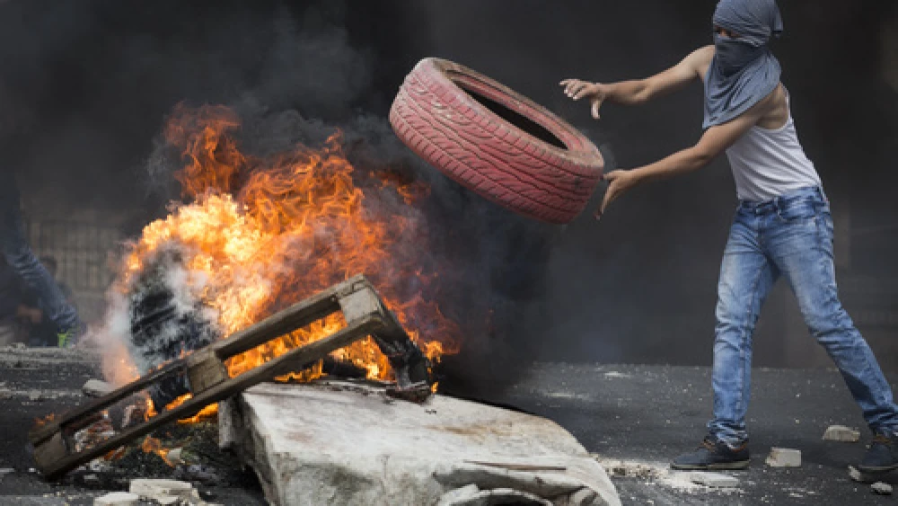 Click photo to download. Caption: On Oct. 7, 2015, a Palestinian rioter throws a tire into a fire, blocking a road during clashes with Israeli police in eastern Jerusalem. Credit: Hadas Parush/Flash90.