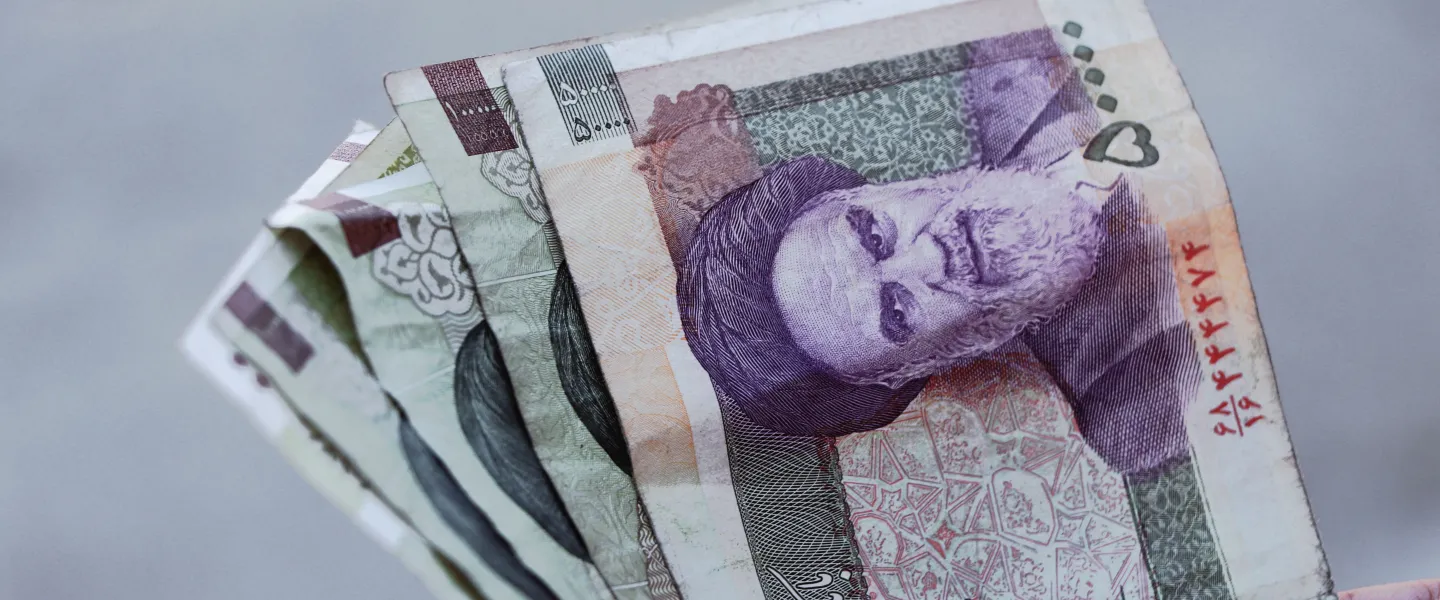 A person holding Iranian rial banknotes. Credit: Amir Ghoorchiani/Pexels.