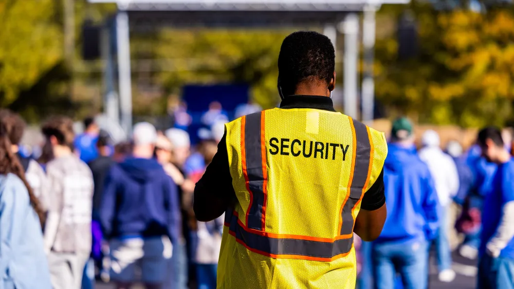 A security guard monitors a crowd at an outdoor event. Credit: Caleb Oquendo/Pexels.