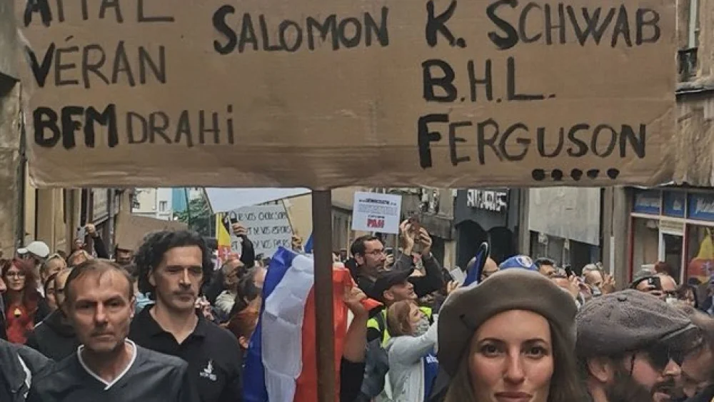 Activist Cassandre Fristot holds an anti-Semitic sign with the names of Jews at a protest in Metz, France, against French protocols regarding the coronavirus, Aug. 12, 2021. Source: Twitter.