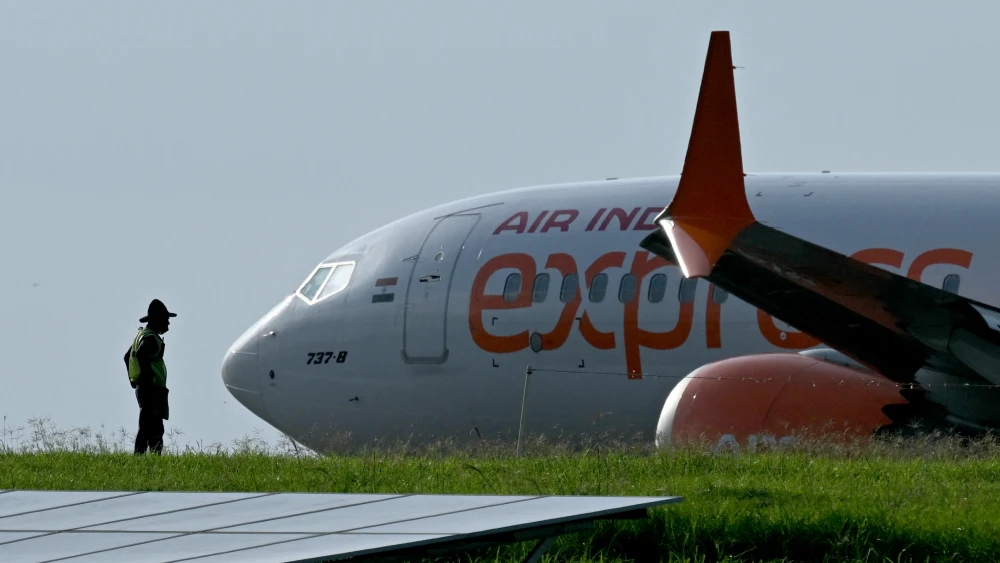 A ground staff member looks on as an Air India aircraft lands at Kempegowda International Airport in Bengaluru on June 10, 2026. Photo by Idrees Mohammed/AFP via Getty Images.