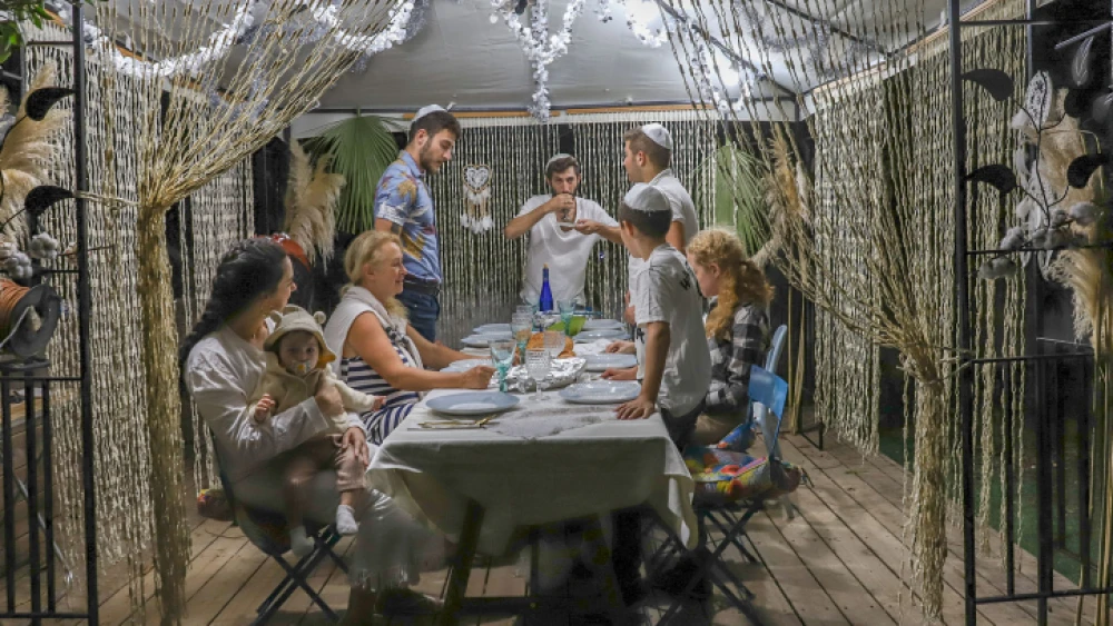 A Jewish family sits in a sukkah in Moshav Yashresh on Oct. 2, 2020. Photo by Yossi Aloni/Flash90.
