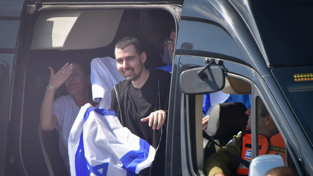 Released hostage Guy Gilboa-Dalal waves the Israeli flag as he arrives to Beilinson hospital, Oct. 13, 2025. Photo by Avshalom Sassoni/Flash90.