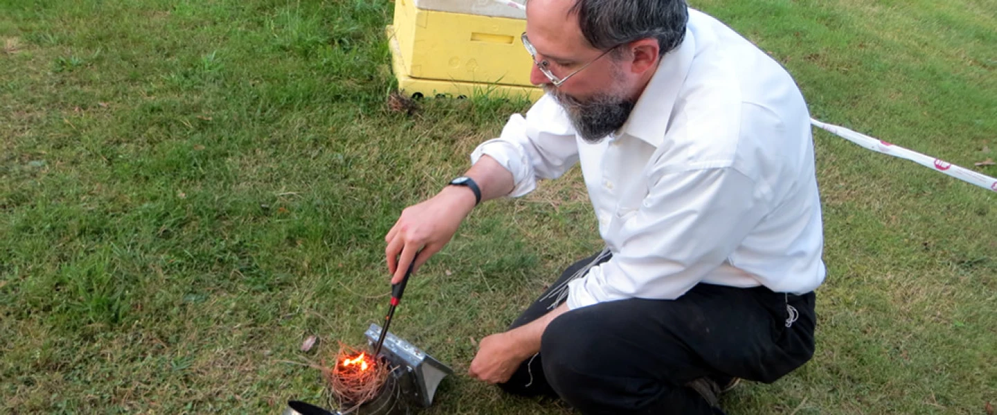 Rabbi Avraham Laber, co-director of Chabad-Lubavitch of Southern Rensselaer County in New York, uses smoke to calm honey bees before opening a hive. Photo by Carin M. Smilk.