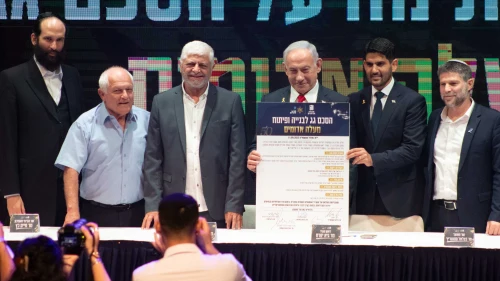 Israeli Prime Minister Benjamin Netanyahu holds up the umbrella agreement at a signing ceremony at the Maale Adumim Cultural Center. Also on stage (from left) are Ministry of Construction and Housing Director-General Yehuda Morgenstern, Housing Minister Haim Katz, former Maale Adumim Mayor Benny Kashriel, current Maale Adumim Mayor Guy Yifrach, and Finance Minister Bezalel Smotrich, Sept. 11, 2025. Photo by David Isaac.