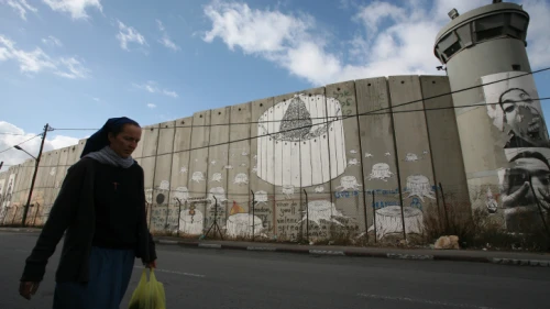 A nun hurries by the Judea and Samaria security barrier toward an IDF checkpoint on her way from Jerusalem to the Church of Nativity in Bethlehem, Dec. 11, 2008. Photo by Yossi Zamir/Flash90.