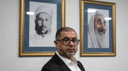 Basem Naim, a member of Hamas's political bureau poses in front of portraits of Izz ad-Din al Qassam (left) and Ahmad Yasin during an interview with AFP in Istanbul on Feb. 8, 2025. Photo by Ozan Kose/AFP via Getty Images)