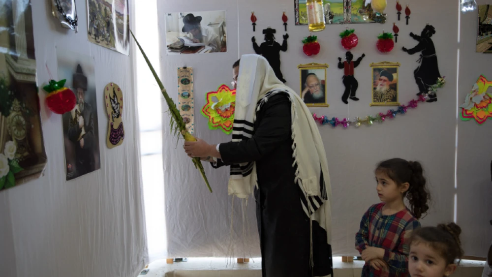 A man waves a lulav in a sukkah in Beitar Illit on Oct. 7, 2020. Photo by Nati Shohat/Flash90.