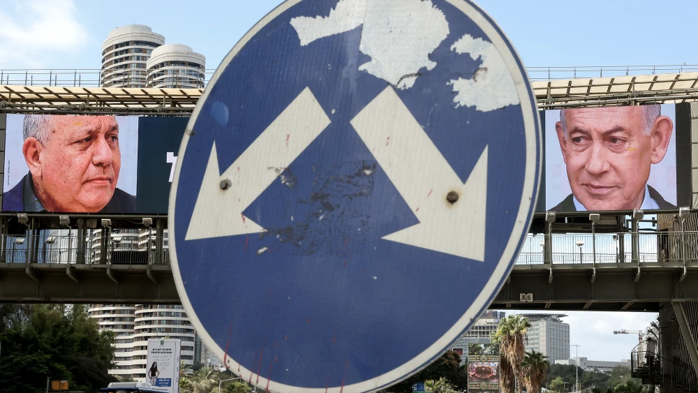 A road sign stands in front of a large billboard featuring Israel's Prime Minister Benjamin Netanyahu (R) of the Likud Party and former military chief and leader of the Yashar Party, Gadi Eisenkot, in Ramat Gan, Oct. 20, 2026. Israel heads to the polls on Oct. 27 in its first election since the Oct. 7, 2023, Hamas-led attack, in what is seen as a referendum on the prime minister. Photo by Jack Guez/AFP via Getty Images.