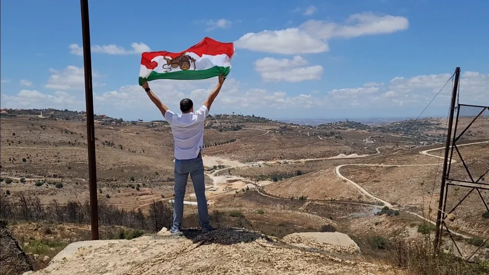 Ahmad Batebi, an Iranian non-Jewish activist and journalist waving the “Sun and Lion” Iranian flag that was used during the Pahlavi dynasty, in Israel. Credit: Courtesy.