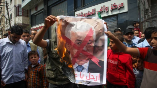 Palestinians burn a crossed poster depicting Palestinian Authority leader Mahmoud Abbas in Khan Younis in southern Gaza on April 14, 2017. Photo by Abed Rahim Khatib/Flash90.