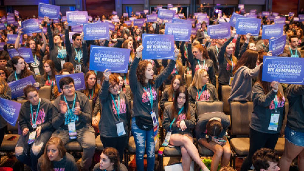 Delegates hold signs stating “We Remember” in five languages at the BBYO International Convention’s Friday-morning plenary session Feb. 17, 2018. Credit: Jason Dixson Photography.