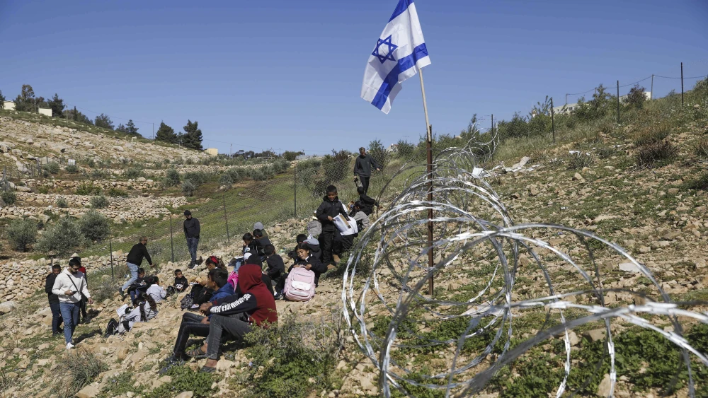 Palestinian students from Umm Al-Kheir are seen next to a newly erected fence around the Israeli community of Carmel, on April 13, 2026. Photo by Wisam Hashlamoun/Flash90.