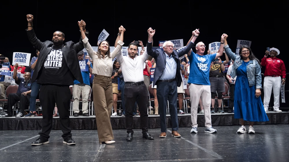 Michigan State Rep. Donavan McKinney, Rep. Alexandria Ocasio-Cortez (D-N.Y.), Michigan Democratic candidate for Senate Dr. Abdul El-Sayed, Sen. Bernie Sanders (I-Vt.), U.A.W. President Shawn Fain and Rep. Rashida Tlaib (D-Mich.) greet the crowd after El-Sayed spoke at The People V. The Powerful rally at the Detroit Opera House in Michigan on July 18, 2026. Photo by Sarah Rice/Getty Images.