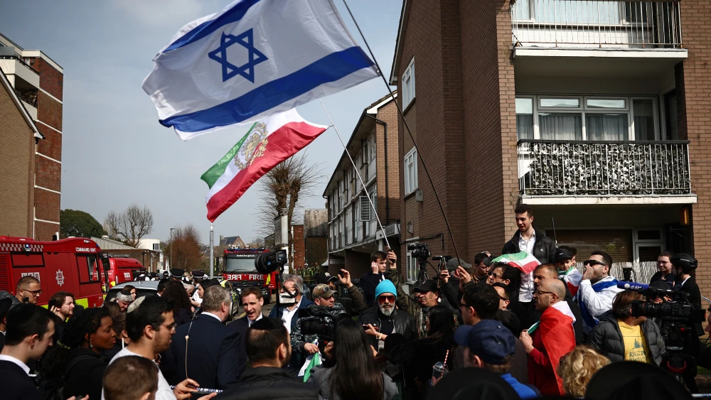 An Iranian flag before the 1979 revolution, with the Lion and Sun emblem, and an Israeli flag are on display at the scene of an antisemitic arson attack in the Golders Green neighborhood of North London on March 23, 2026. Photo by Henry Nicholls/AFP via Getty Images.