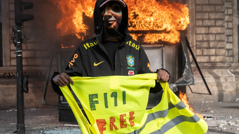 A protester holds a yellow vest as a bus stop burns during a demonstration at Place de Republique in Paris, France, Oct. 17, 2026 . Photo by Guy Smallman/Getty Images.