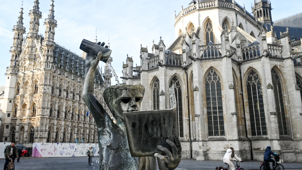 Cyclists ride past a statue in Leuven, Belgium on Jan. 22, 2026. Photo by ELIAS ROM / Belga / AFP via Getty Images.