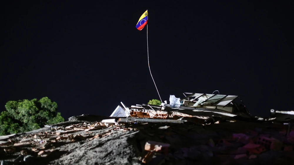 A Venezuelan flag raised above the debris of a demolished building in La Guaira after two earthquakes struck the country and other regions in the Caribbean, June 27, 2026. Photo by Jesus Vargas/Getty Images.