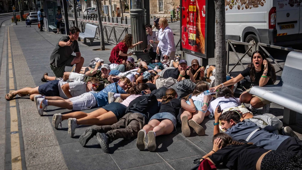 People take cover as sirens warns of incoming missile fire from Yemen in Jerusalem, March 27, 2025. Photo by Chaim Goldberg/Flash90.