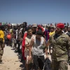 Migrants wait to receive water on the beach next to the CETI (Centros de Estancia Temporal de Inmigrantes) in Ceuta, Spain, on Aug. 2, 2026. Spain's interior ministry deployed members of the armed forces and Guardia Civil officers there after tens of thousands of migrants suddenly entered the Spanish enclave in North Africa.