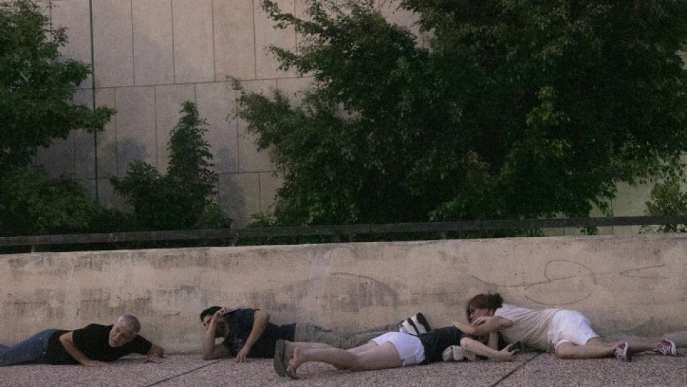 Israelis take cover as a rocket warning siren sounds in "Hostage Square" outside the Tel Aviv Museum of Art, Oct. 28, 2023. Photo by Miriam Alster/Flash90.