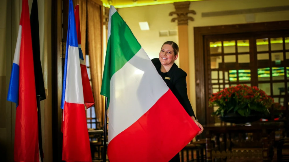 A worker hangs flags at the King David Hotel in Jerusalem ahead of a visit of more than 30 heads of state and ministers from around the world as part of the Fifth World Holocaust Forum, Jan. 16, 2020. Photo by Yonatan Sindel/Flash90.