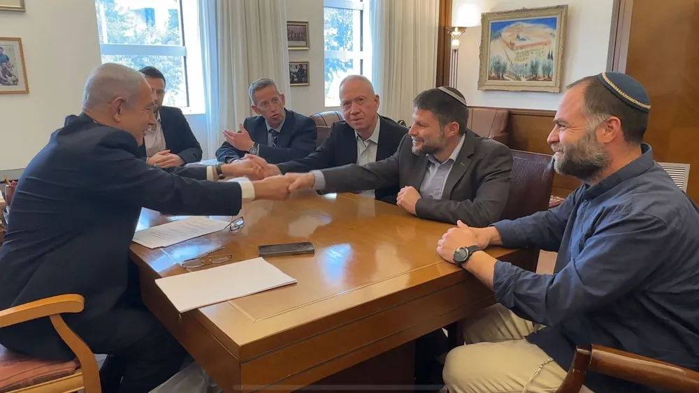Israeli Prime Minister Benjamin Netanyahu (left), Defense Minister Yoav Gallant (shaking Netanyahu's left hand) and Minister in the Defense Ministry Bezalel Smotrich (shaking Netanyahu's right hand) sign a document of understandings on the division of responsibility in the Defense Ministry, on Feb. 23, 2023. Credit: Courtesy.