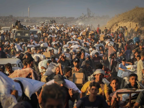 Palestinians carry food parcels and supplies from aid trucks near the Zikim border crossing between Israel and Beit Lahia, in the northern Gaza Strip, Aug. 18, 2025. Photo by Khalil Kahlout/ Flash90.