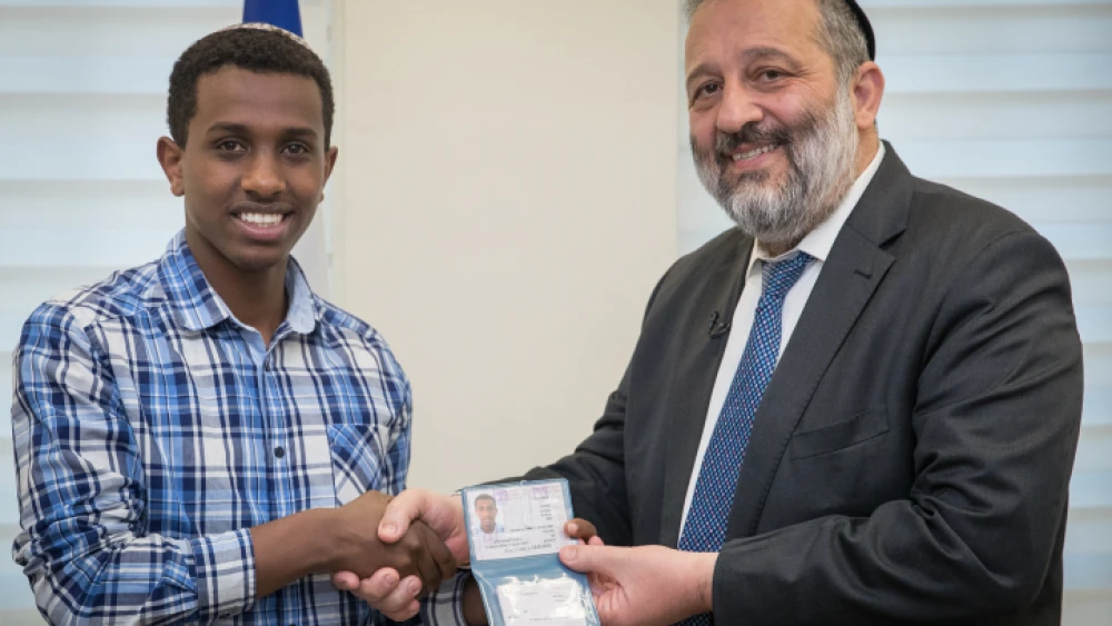 Sintayehu Shaparau from Ethiopia, who is competing in the annual International Bible Quiz in Israel, is handed a national ID form by Israel Minister of Interior Affairs Aryeh Deri during a ceremony at the Interior ministry office in Jerusalem on April 16, 2018. Photo by Yonatan Sindel/Flash90
