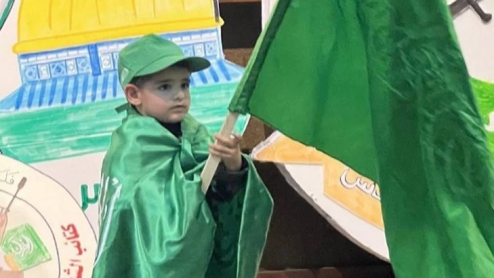 A boy holds a Hamas flag at the Al-Quds University event on Dec. 11, 2022. Source: T.me/kotlaalquds via MEMRI.