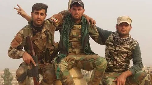 Assyrian Christian pose in front a newly erected cross atop the Mar Shmony church in the liberated town of Bartella, Iraq. Credit: Nineveh Plains Protection Unit.