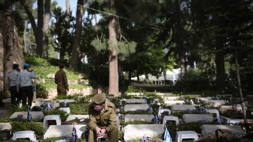 An Israeli soldier sits next to grave of fallen soldier at the Mount Herzl military cemetery in Jerusalem during Israeli Memorial Day, which commemorates the deaths of Israeli soldiers killed in wars since 1860, as well as Israeli victims of terror. April 18, 2018. Photo by Miriam Alster/Flash90