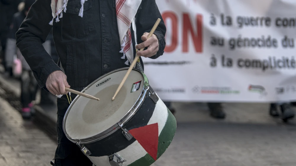 A demonstrator plays a drum decorated with the Palestinian flag while protesting against the United States and Israel for initiating the Middle East war in Montreal, Quebec, Canada, on March 21, 2026. Photo by Andrej Ivanov / AFP via Getty Images.