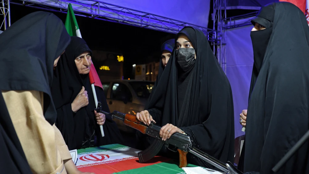An Iranian military personnel (C) educates women about how to use a gun at a booth in Hafte Tir Square, in Tehran on May 17, 2026. Photo by AFP via Getty Images.